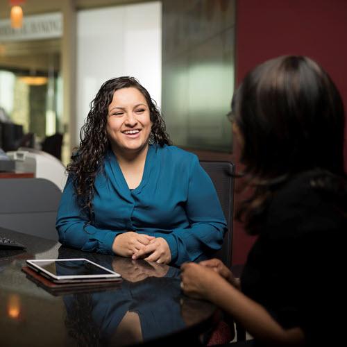 Banker smiling at desk looking at customers