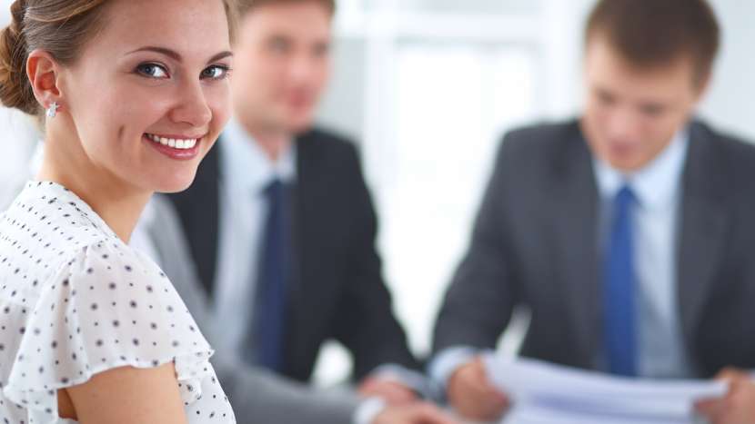 woman smiling with co workers blurred in background