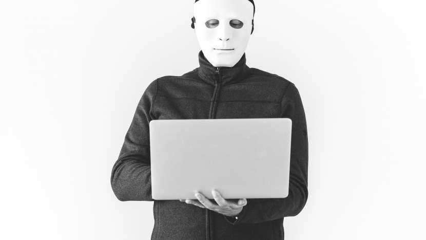 man in mask using laptop