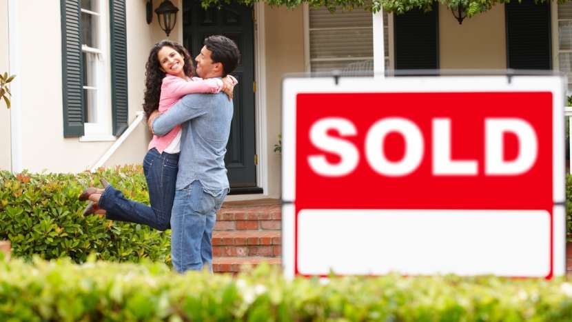 Sold Sign with happy couple in the background