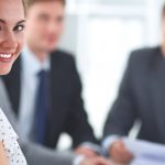 woman smiling with co workers blurred in background