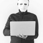man in mask using laptop