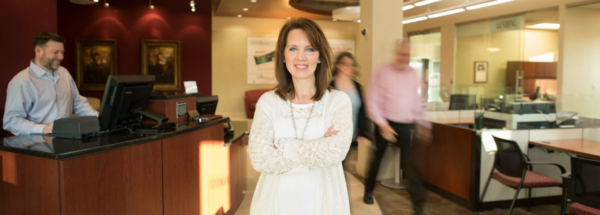 With us, banking is personal - woman standing in lobby smiling