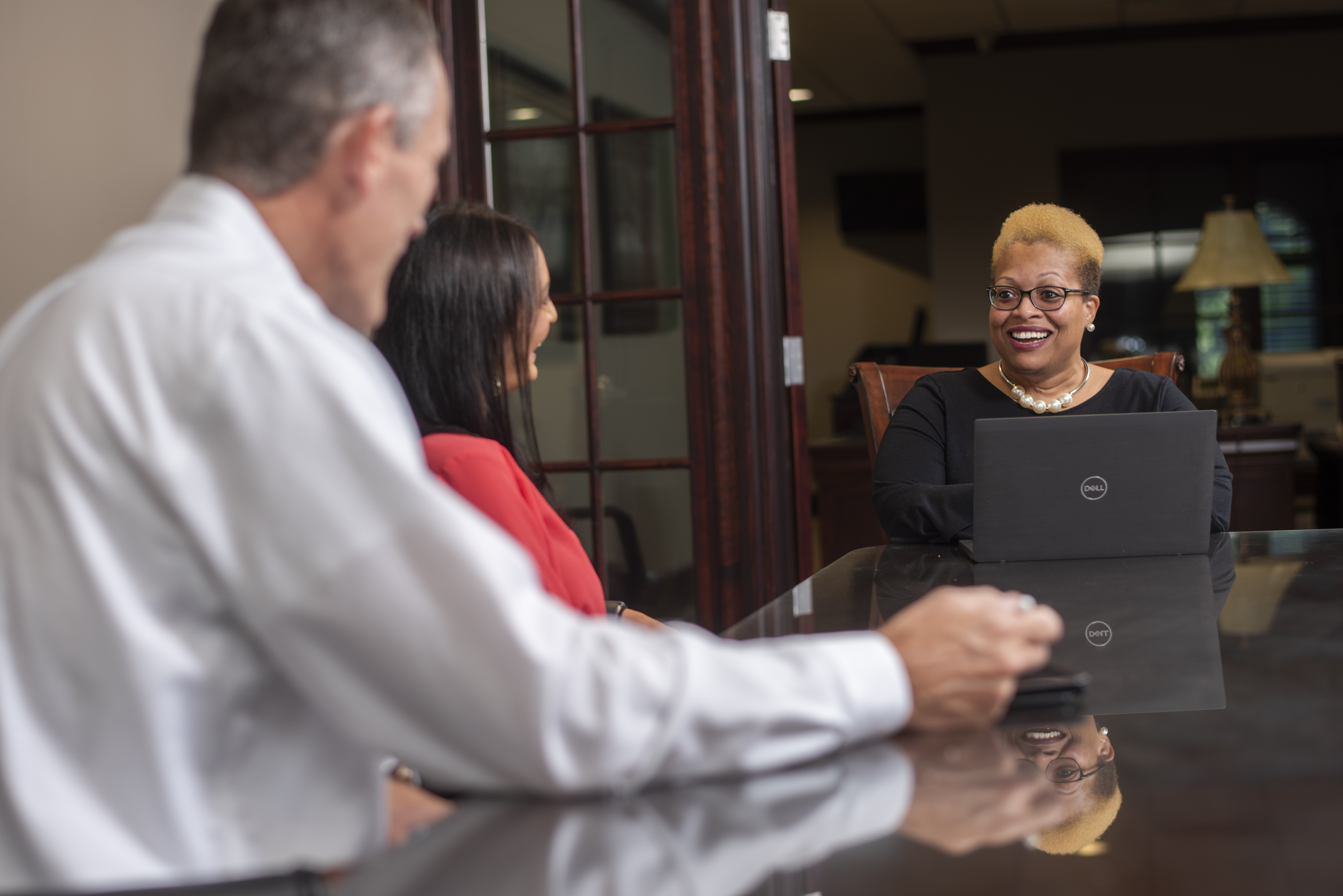 Three people talking to each other at a conference table